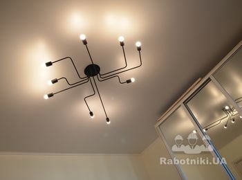 Смонтирована люстра для жесткого потолка со смещенным центром тяжести на натяжной. Сложно, но возможно.