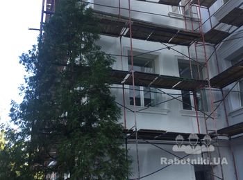 Устройство утепления фасада старого здания с декорированными элементами.
