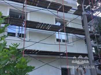 Устройство утепления фасада старого здания с декорированными элементами.