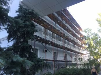 Устройство утепления фасада старого здания с декорированными элементами.