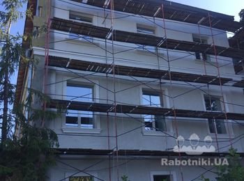 Устройство утепления фасада старого здания с декорированными элементами.