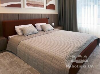 Інтер'єр спальні бежевого відтінку, з бордовим узголів'ям, шпонованими стіновими панелями світлого дерева, декоративними арт-панелями