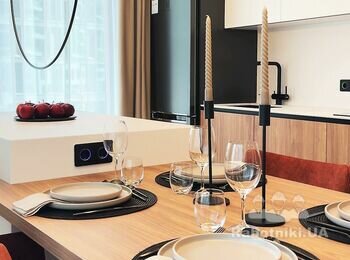 Сучасна кухня після ремонту, дерев'яний стіл, острівець з білого MDF, декоративні світильники над столом