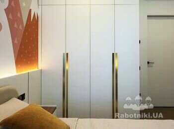 Дитяча з білою шафою до стелі та золотистими ручками та фотошпалерами на стіні