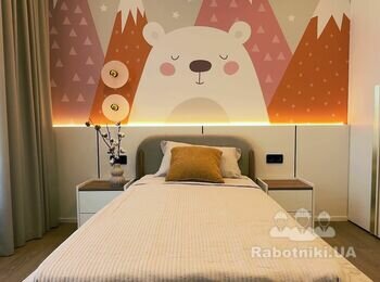 Інтер'єр дитячої кімнати з яскравою стіною із зображенням ведмедика та гір за узголів'ям ліжка
