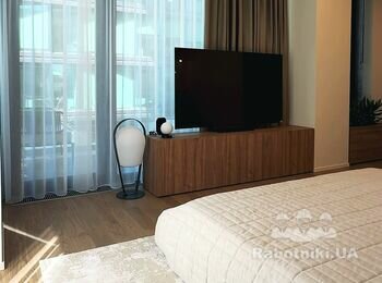 Світла спальня в UnitCity з панорамними вікнами і паркетом, тумба під ТВ зі шпонованого MDF