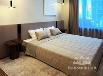 Спальня кімната зі стінами кремового кольору, м'якими стіновими панелями, чорними підвісними світильниками