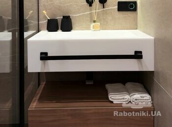 Білий умивальник зі штучного каменю, чорним змішувачем вбудованим в стіну, тумбою зі шпонованого МДФ