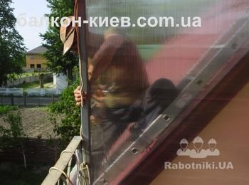 Оказалось не так - то просто установить стенку на каркас навеса. Доступ в рабочую зону осложнен. На помощь приходит та - же лестница. Привязываем её к каркасу и укладываем на крышу дома. Фото сделано снизу, с пола балкона.